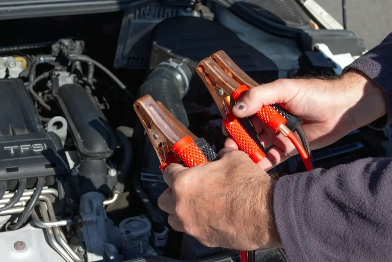 person holding red and black battery terminals
